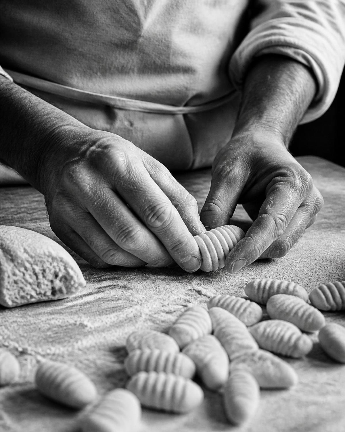 Le mani che rigano i gnocchi di fioretta sul tagliere